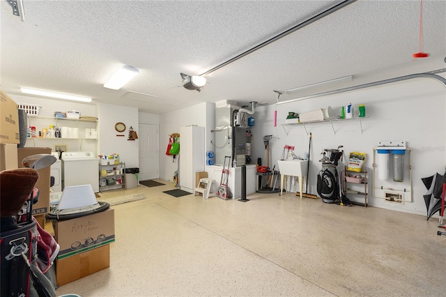 garage featuring washing machine and clothes dryer, a garage door opener, and heating unit