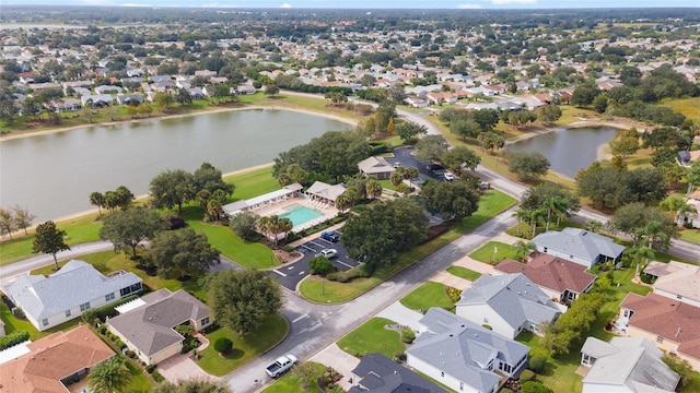 aerial view of property and surrounding area featuring a large body of water, nearby suburban area, and a pool area