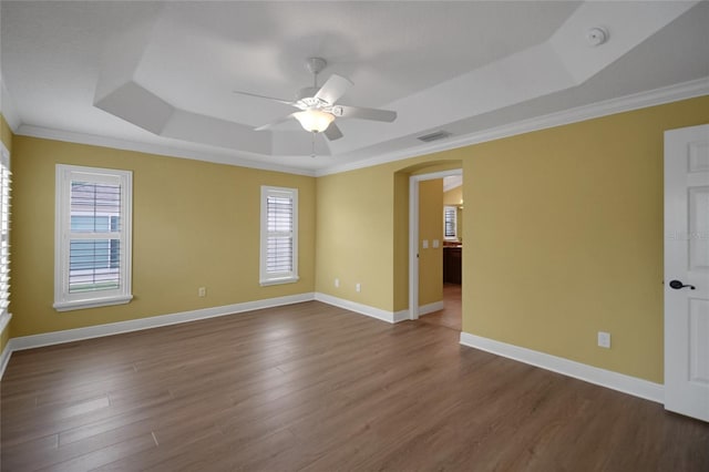 1828 Hollow Branch Way, The Villages, FL 32162 - empty room featuring a raised ceiling, a ceiling fan, arched walkways, crown molding, and dark wood-style flooring
