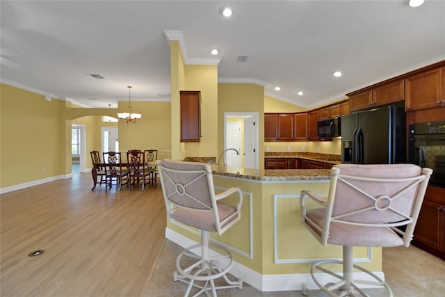 1828 Hollow Branch Way, The Villages, FL 32162 - kitchen with black appliances, ornamental molding, arched walkways, a chandelier, and light wood-style flooring
