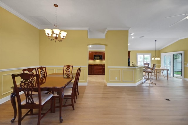 1828 Hollow Branch Way, The Villages, FL 32162 - dining space with a chandelier, light wood finished floors, ornamental molding, arched walkways, and a wainscoted wall