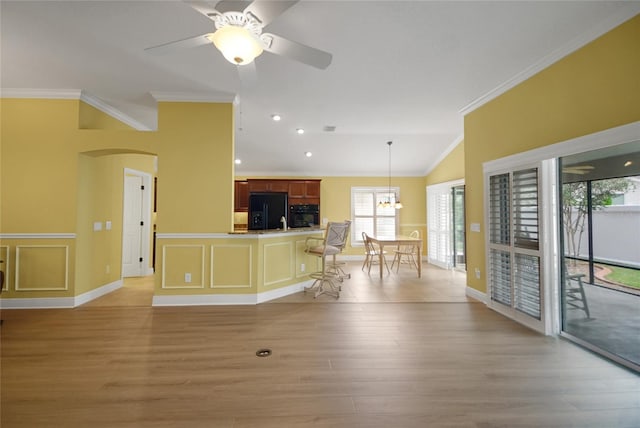 1828 Hollow Branch Way, The Villages, FL 32162 - living area featuring crown molding, light wood-type flooring, vaulted ceiling, a ceiling fan, and arched walkways