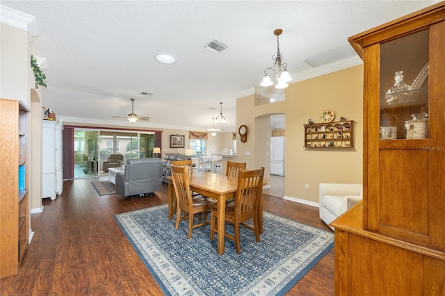616 Hartford Ln, The Villages, FL 32162 - dining area featuring arched walkways, ornamental molding, a chandelier, ceiling fan, and dark wood-style floors