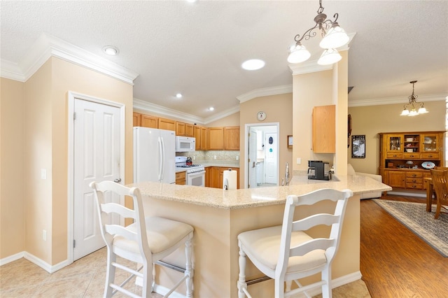 616 Hartford Ln, The Villages, FL 32162 - kitchen featuring white appliances, a chandelier, a peninsula, ornamental molding, and a breakfast bar