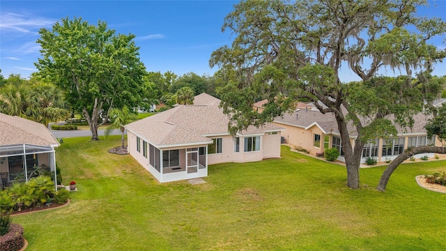 12687 SE 90th Ter, Summerfield, FL 34491 - back of house with a sunroom, a yard, stucco siding, and a shingled roof