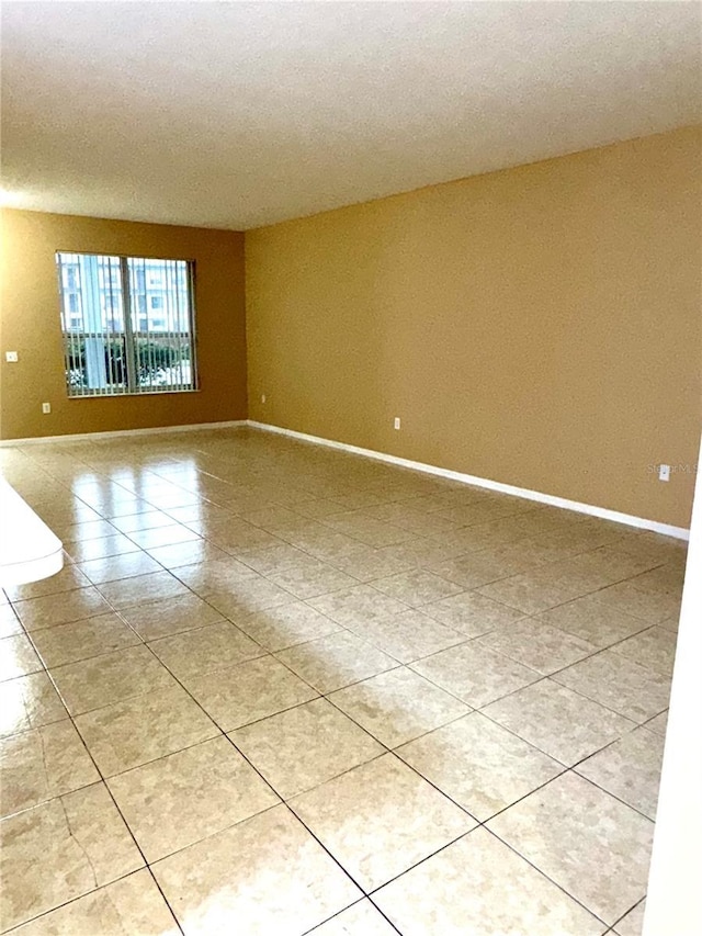 unfurnished room featuring light tile patterned floors and baseboards