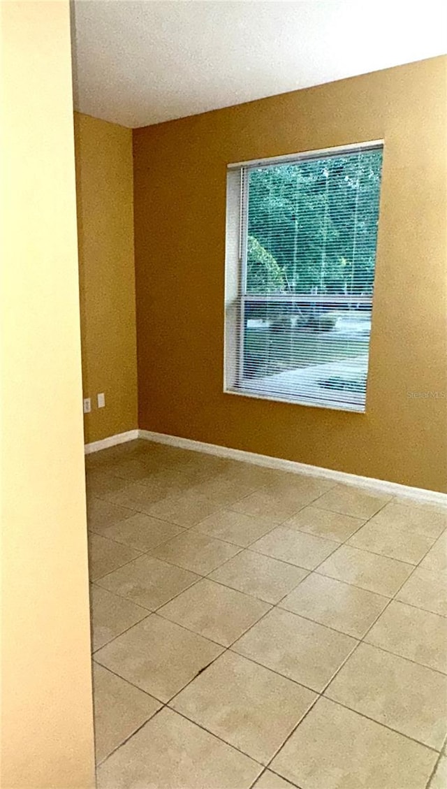 spare room featuring light tile patterned floors and baseboards
