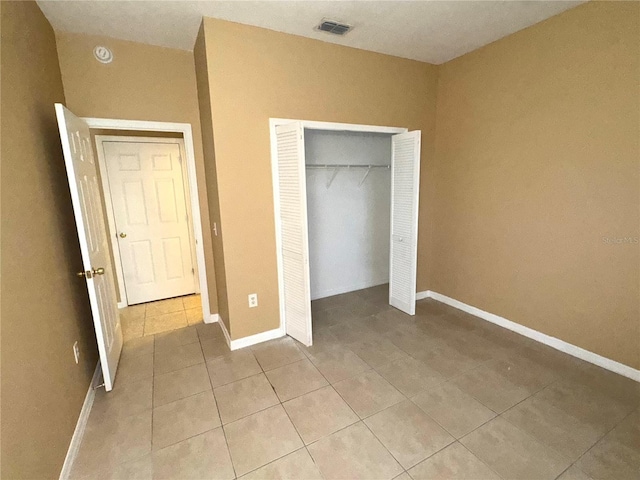 unfurnished bedroom featuring light tile patterned floors, a closet, and baseboards