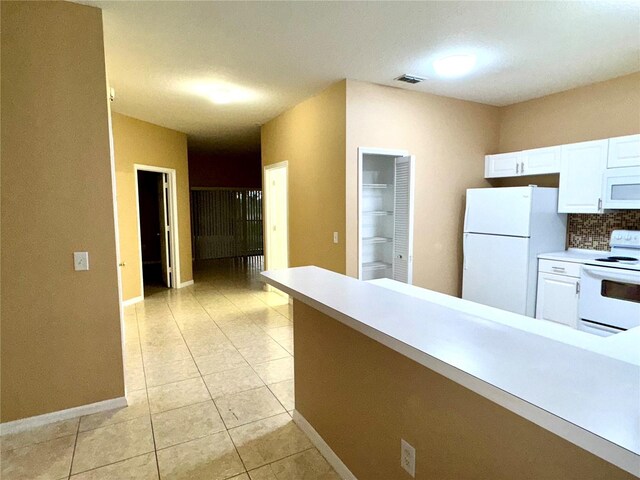 kitchen with white appliances, white cabinets, light tile patterned floors, light countertops, and baseboards