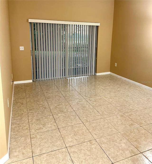 tiled spare room featuring baseboards