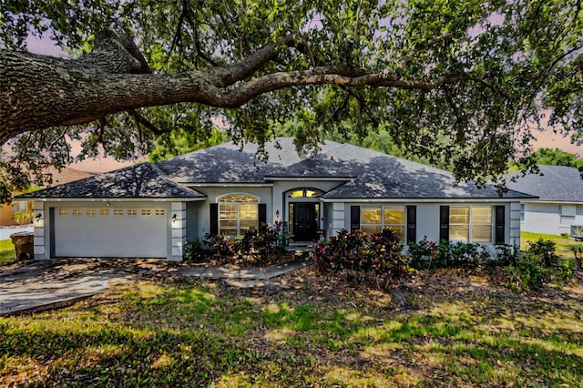 ranch-style home featuring stucco siding, an attached garage, roof with shingles, and concrete driveway