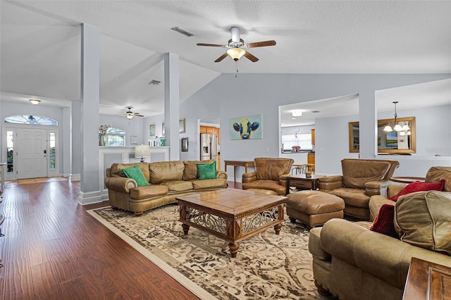 living room with ceiling fan, lofted ceiling, wood finished floors, a chandelier, and a textured ceiling