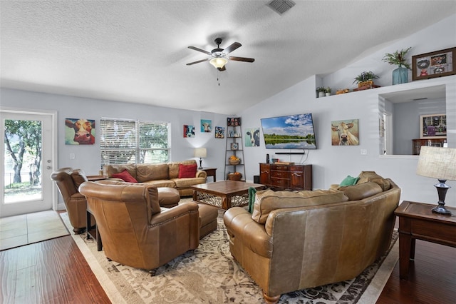 living area with lofted ceiling, ceiling fan, plenty of natural light, a textured ceiling, and light wood finished floors