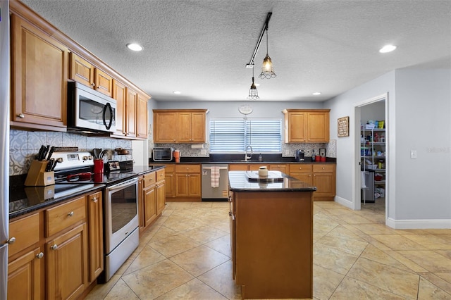 kitchen featuring stainless steel appliances, a center island, tasteful backsplash, a textured ceiling, and brown cabinets
