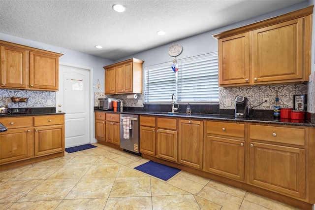 kitchen with dishwasher, a sink, brown cabinets, decorative backsplash, and a textured ceiling