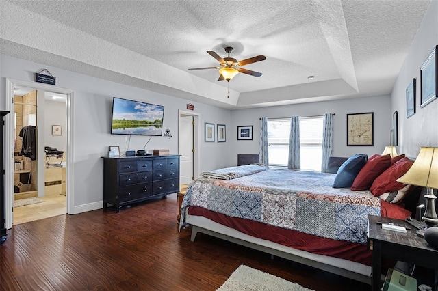 bedroom featuring a raised ceiling, wood finished floors, a textured ceiling, ceiling fan, and baseboards
