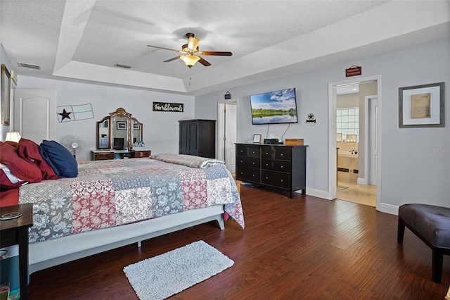bedroom with a raised ceiling, wood finished floors, baseboards, a textured ceiling, and ceiling fan