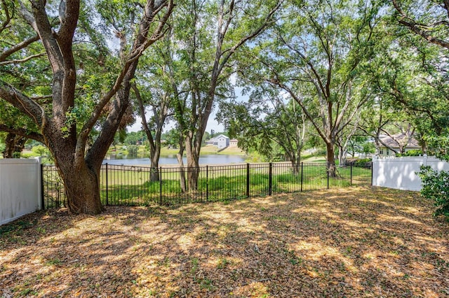 fenced backyard featuring a water view