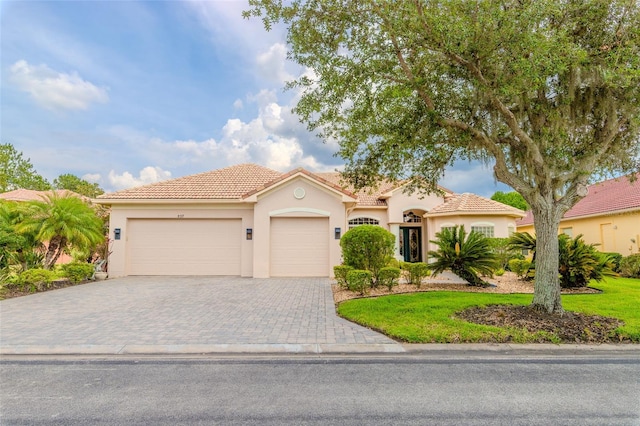 537 Montage Ln, Kissimmee, FL 34759 - mediterranean / spanish-style house featuring stucco siding, a tile roof, a garage, and decorative driveway