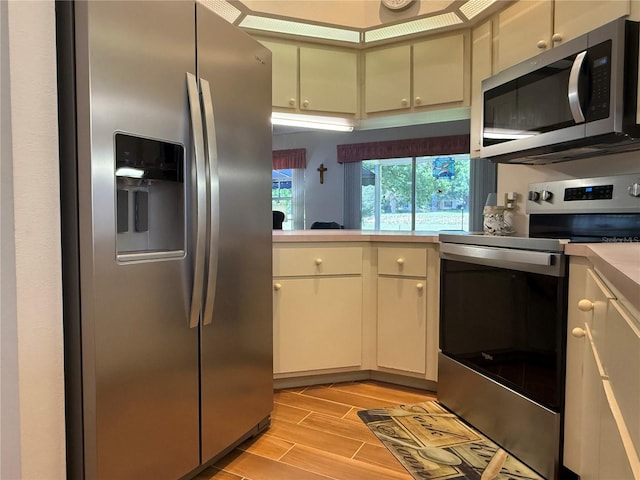 239 Juniper Way, Tavares, FL 32778 - kitchen with stainless steel appliances, light countertops, light wood-style flooring, and cream cabinetry