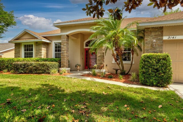 3141 Brighton Rd, Eustis, FL 32726 - view of front of house with stone siding, a garage, a front yard, and stucco siding