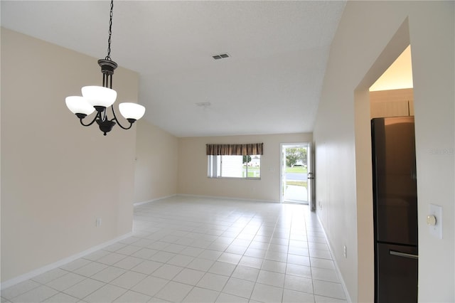 spare room with a chandelier, vaulted ceiling, light tile patterned floors, and baseboards