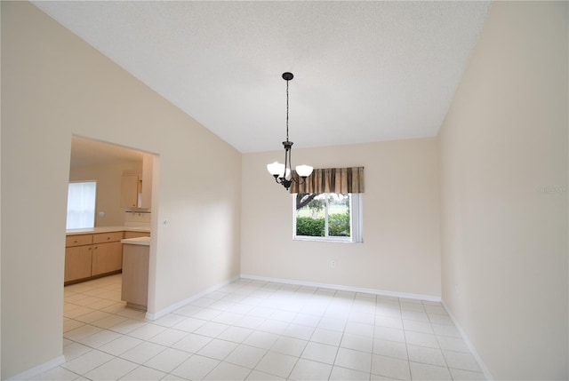 spare room featuring lofted ceiling, a chandelier, light tile patterned flooring, and baseboards