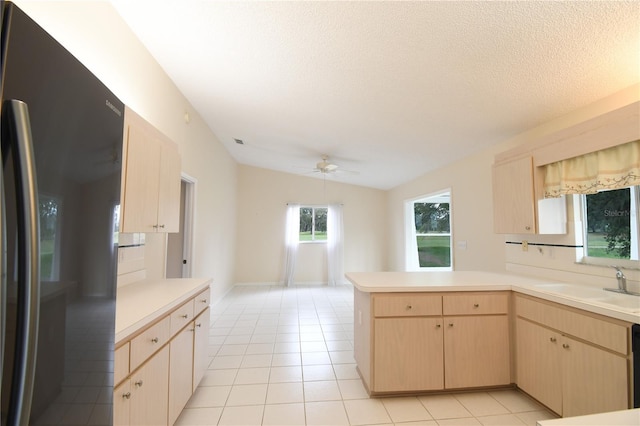 kitchen with black refrigerator with ice dispenser, light brown cabinetry, a sink, a peninsula, and a ceiling fan