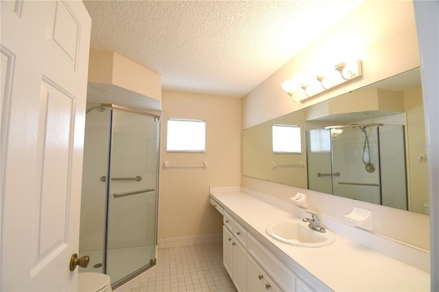 bathroom with a shower stall, a textured ceiling, vanity, tile patterned floors, and baseboards
