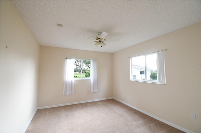 empty room featuring ceiling fan, light colored carpet, baseboards, a textured ceiling, and a smoke detector