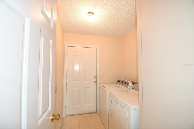 laundry area with washing machine and dryer and a textured ceiling