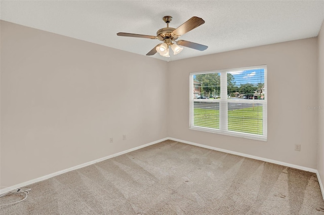 carpeted spare room featuring baseboards and a ceiling fan