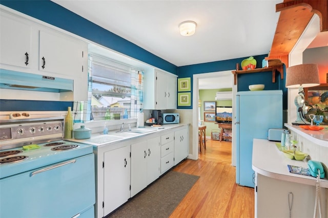 1301 N Ave, Tavares, FL 32778 - kitchen with electric range oven, under cabinet range hood, a sink, light countertops, and white cabinetry