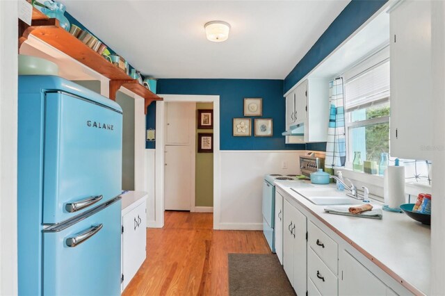 1301 N Ave, Tavares, FL 32778 - kitchen featuring white electric range oven, freestanding refrigerator, a sink, under cabinet range hood, and white cabinets