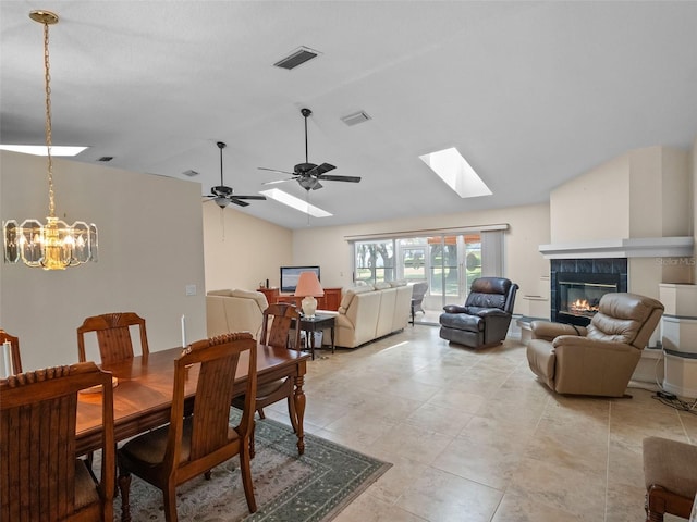 dining space featuring lofted ceiling, a fireplace, a skylight, a chandelier, and light tile patterned flooring