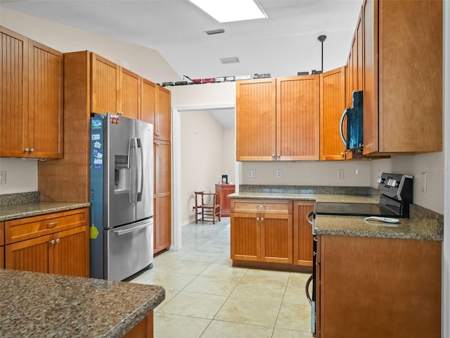 kitchen featuring appliances with stainless steel finishes, dark countertops, lofted ceiling, light tile patterned floors, and brown cabinetry