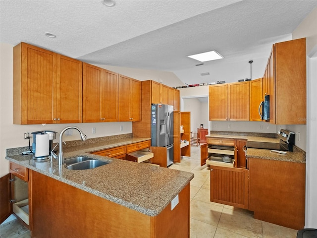kitchen featuring appliances with stainless steel finishes, a sink, vaulted ceiling, a peninsula, and light stone counters