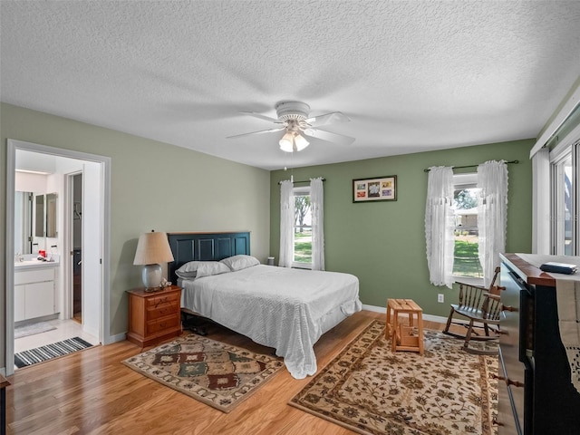 bedroom featuring wood finished floors, baseboards, a textured ceiling, a ceiling fan, and ensuite bathroom