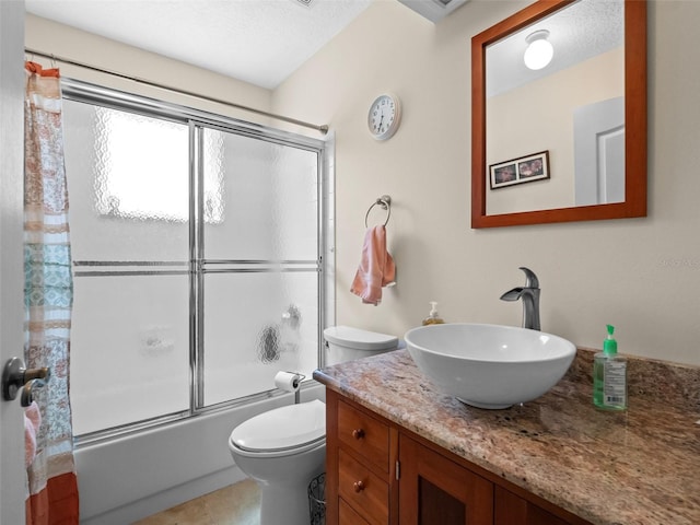 bathroom featuring toilet, enclosed tub / shower combo, vanity, and tile patterned floors
