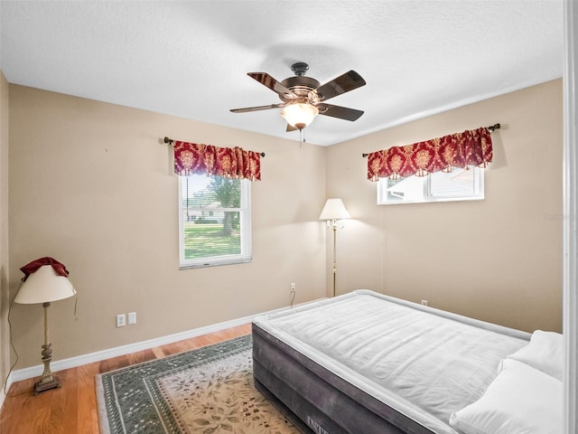 bedroom with wood finished floors, baseboards, and ceiling fan