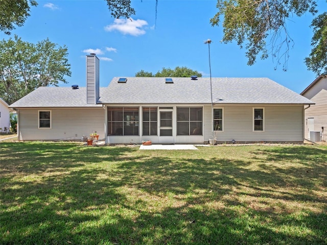 back of house featuring a sunroom, a yard, a chimney, and a shingled roof