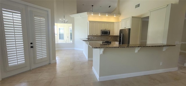8719 Kenmure Cv, Orlando, FL 32836 - kitchen featuring stainless steel appliances, dark stone counters, decorative backsplash, a breakfast bar area, and a chandelier