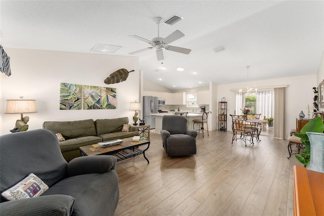 living area featuring lofted ceiling, ceiling fan, light wood-style floors, and a chandelier