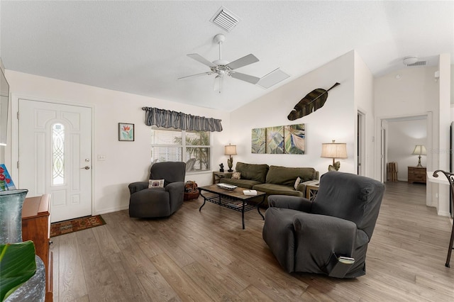 living area with vaulted ceiling, ceiling fan, light wood-style flooring, and baseboards