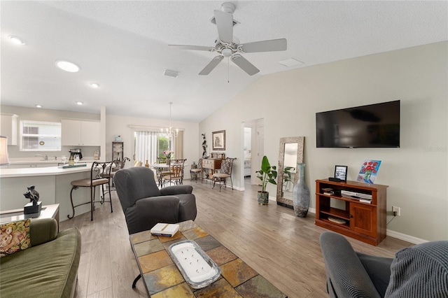 living room with light wood finished floors, a ceiling fan, vaulted ceiling, and baseboards