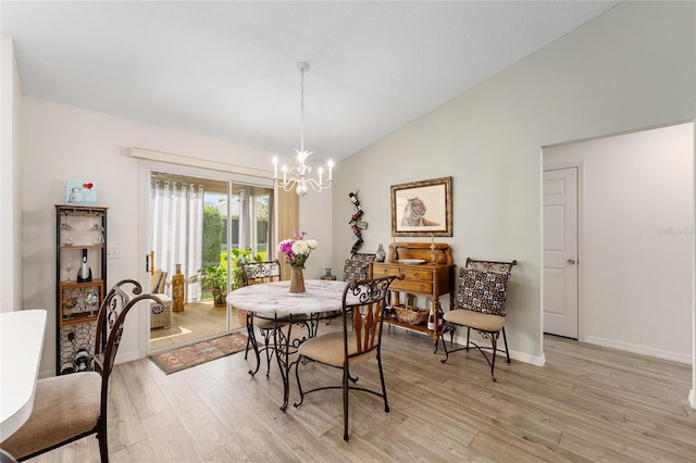 dining room featuring a chandelier, light wood finished floors, vaulted ceiling, and baseboards