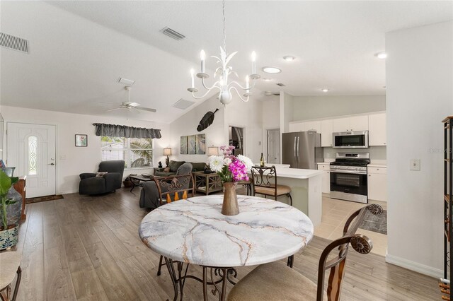 dining area featuring lofted ceiling, light wood-style flooring, baseboards, a ceiling fan, and a chandelier