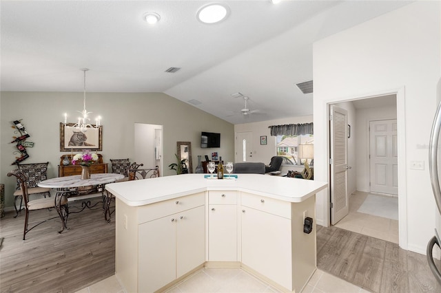 kitchen featuring light wood finished floors, vaulted ceiling, open floor plan, light countertops, and a chandelier