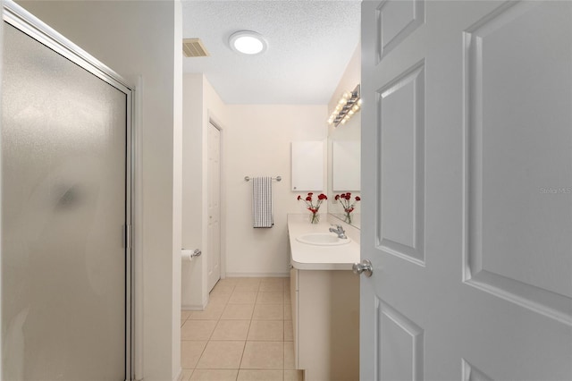 full bathroom with tile patterned floors, vanity, a stall shower, a textured ceiling, and baseboards