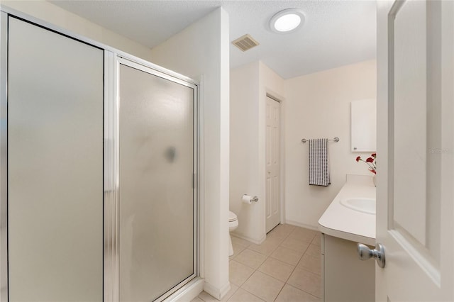 bathroom with tile patterned flooring, a stall shower, toilet, and vanity